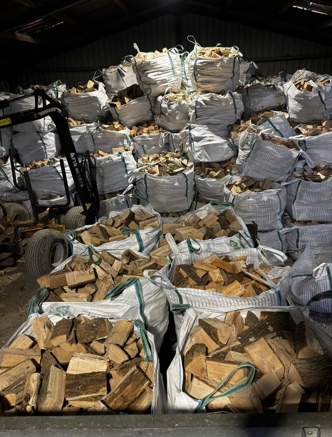 Stacks of bagged seasoned logs filling the barn ready for delivery