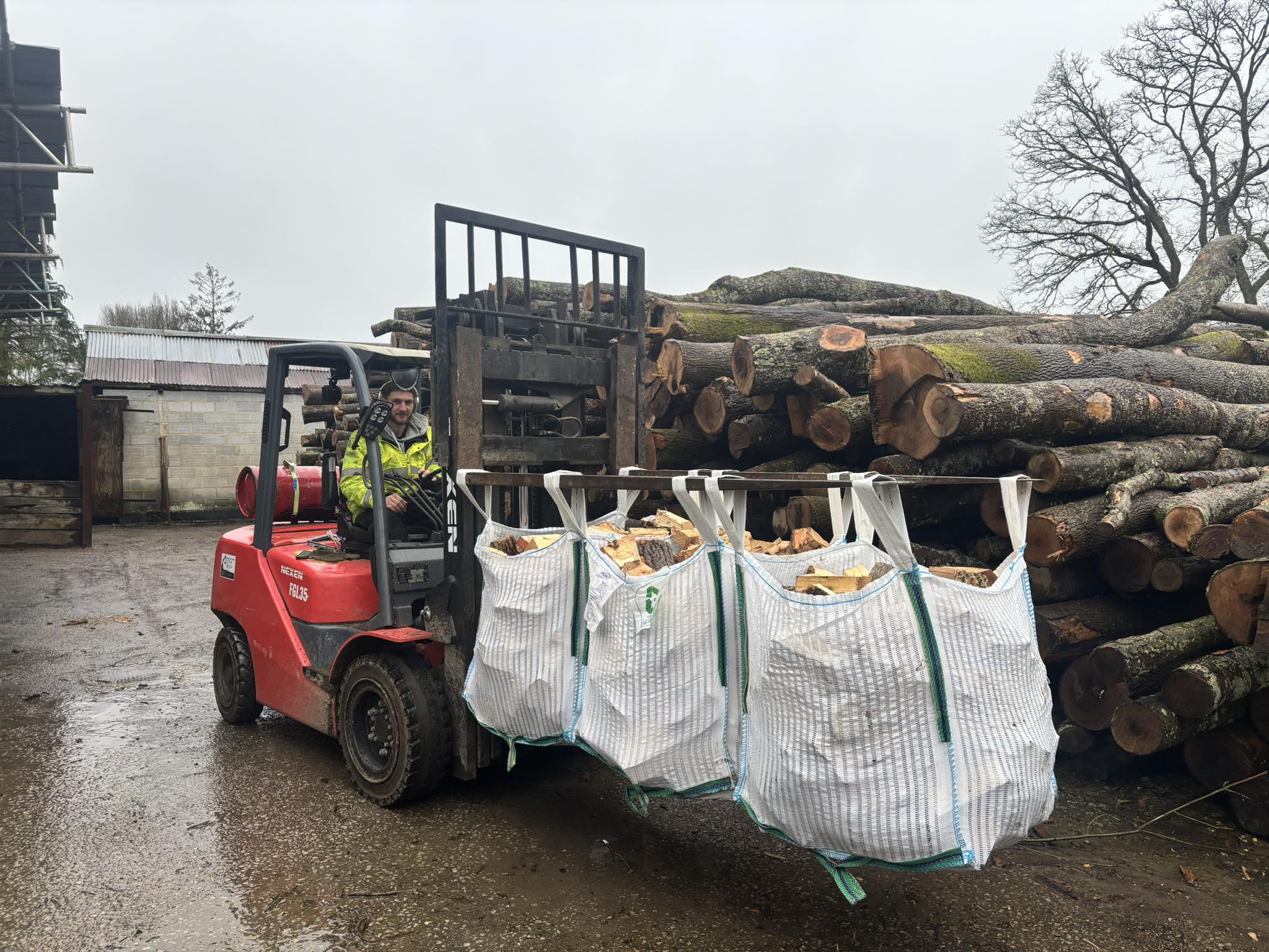 A forklift loading tonne bags of logs onto the delivery truck at the T & H yard