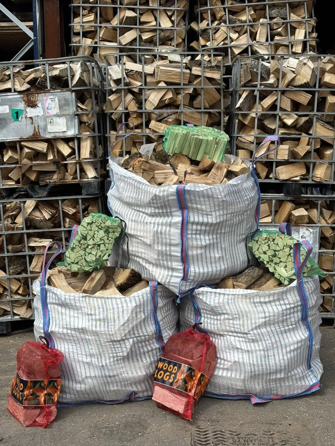 Three bags of split logs with kindling nets and log nets, in front of crates of split wood.