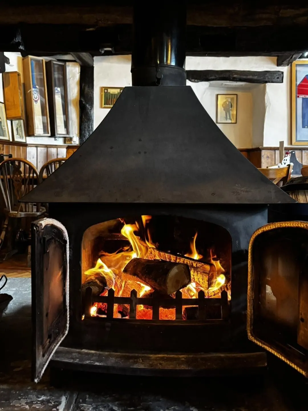 A large stove alight with the doors open, flames burning brightly inside.
